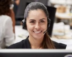 Portrait Of Female Customer Services Agent Working At Desk In Call Center